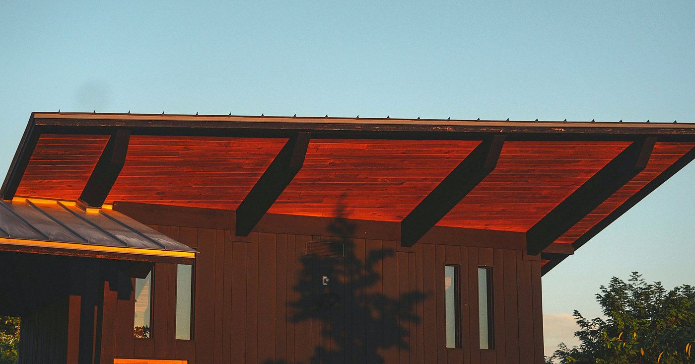 A warm timber soffit under a deep roof overhang at dusk.