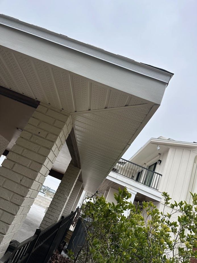 Cream vented soffit over a brick-column porch, viewed from below.