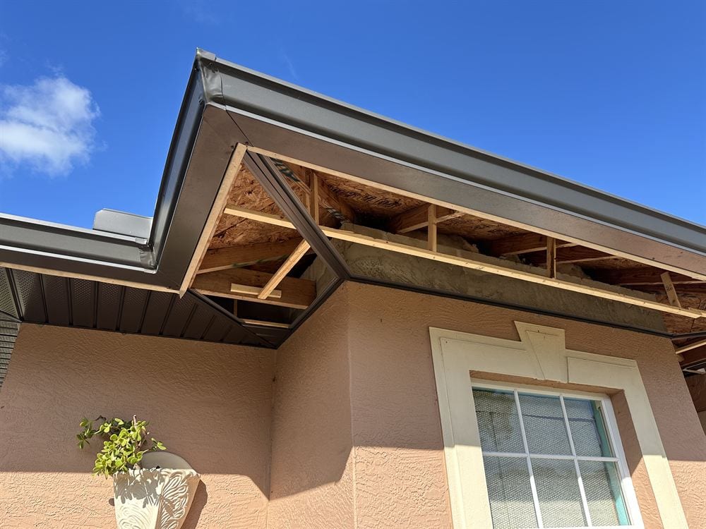 Eave opened up showing bare rafters with new bronze fascia wrap already installed.