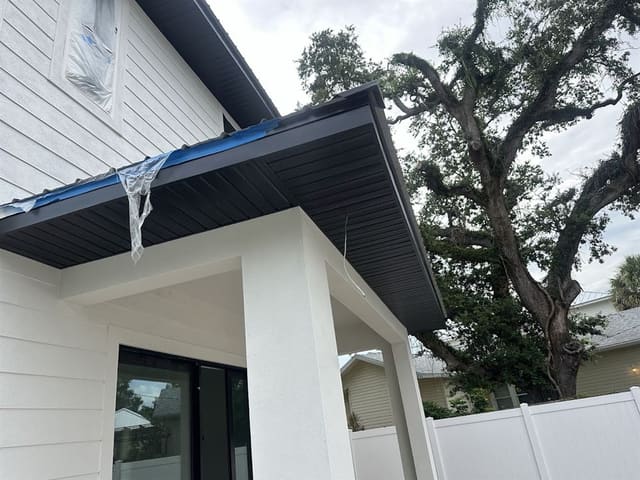 Black vented soffit installed over a porch with painter's tape still in place.