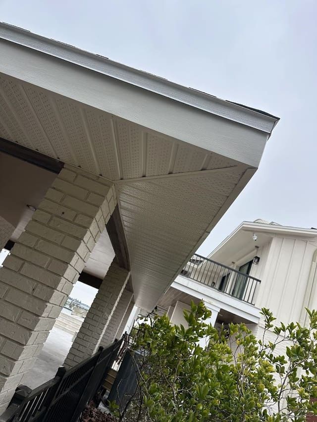 Cream vented soffit over a brick-column porch, viewed from below.