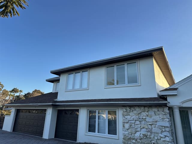 Two-story stucco home in daylight with completed dark soffit and fascia.