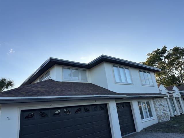 Two-story stucco home at dusk with dark soffit and fascia along the full roofline.