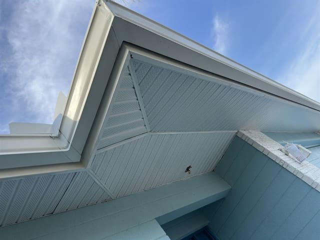 Pale blue vented soffit and white fascia meeting at a gable end.