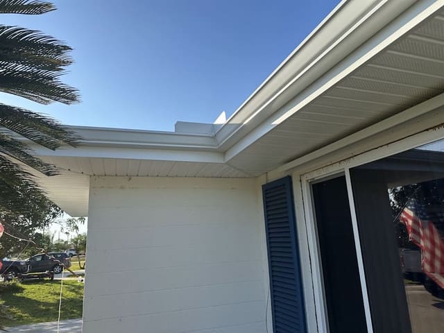New white seamless gutter and vented soffit wrapping the corner of a block home.