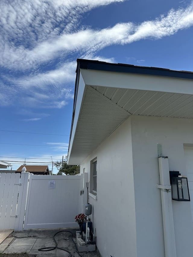 Cream vented soffit and dark fascia along the side elevation of a stucco home.