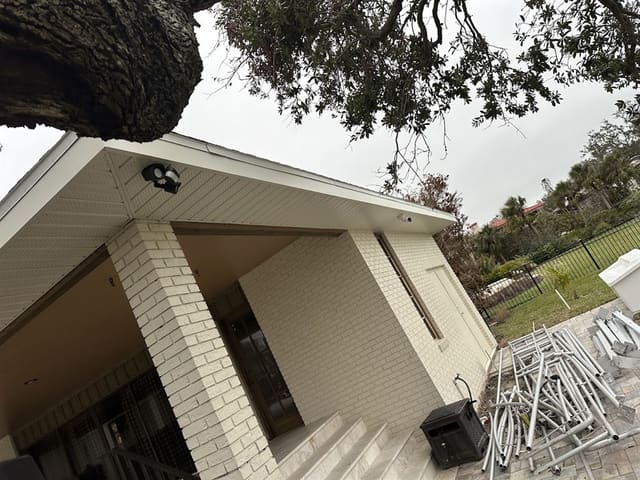 Cream brick home with completed soffit and fascia; scaffolding stacked nearby.