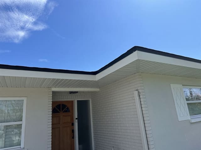 Close view of white vented soffit and black fascia turning the entry corner.