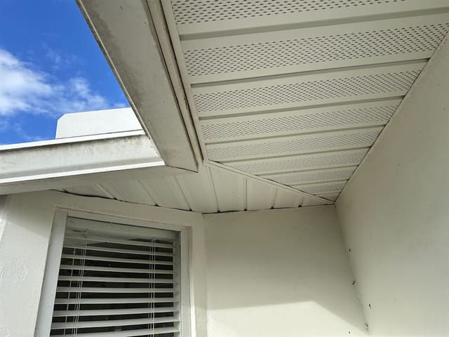 Cream vented aluminum soffit panels fitted into a corner under the eave.