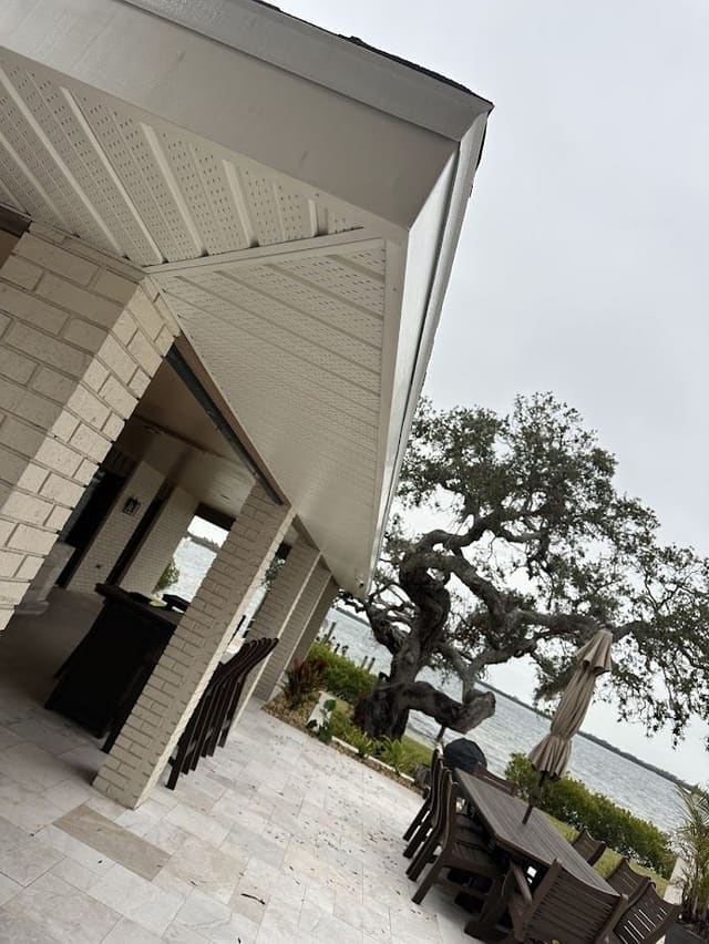 Finished cream soffit above a waterfront patio with brick columns.