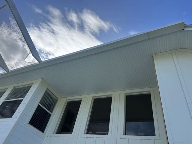 White beadboard soffit along a home's eave beside a screened pool enclosure.