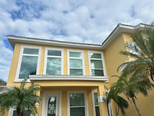 White fascia and soffit tracing the roofline of a yellow stucco two-story home.