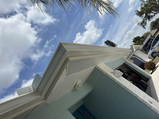 White soffit, fascia and gutter along the roofline of a seafoam block home.
