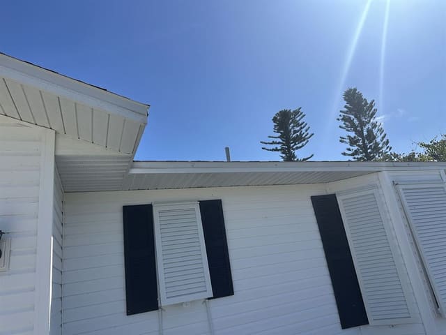 White vented soffit and fascia above white lap siding with black shutters.