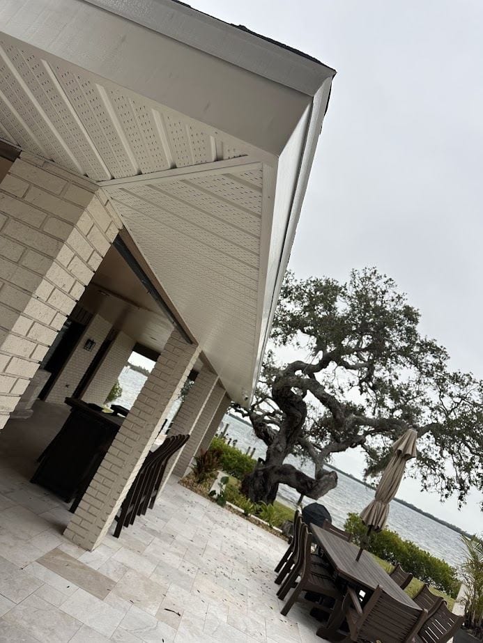 Finished cream soffit above a waterfront patio with brick columns.