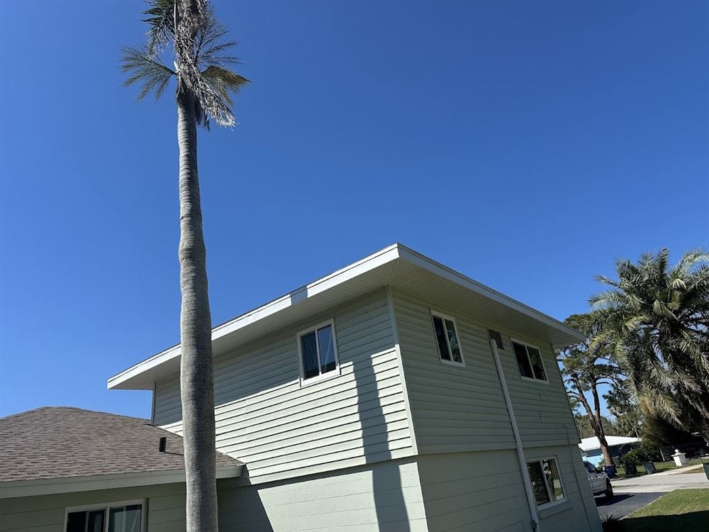 Sage green two-story home with new white soffit and fascia along the roofline.