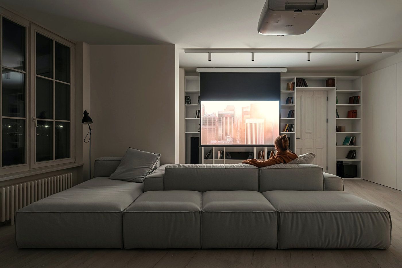A living room with a large projection screen and a long sofa.