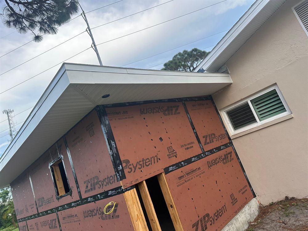 Storm-battered roofline with damaged trim.